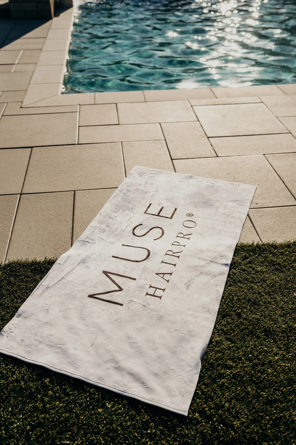 MUSE HAIRPRO striped towel beside a swimming pool