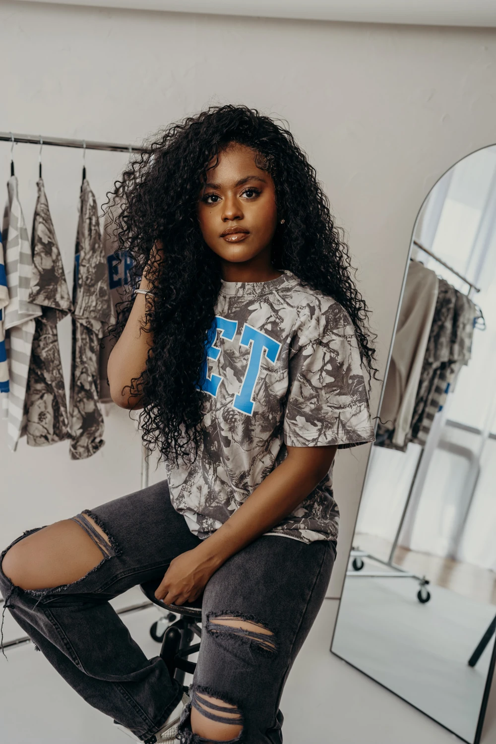 Seated fashion portrait with a clothing rack and mirror